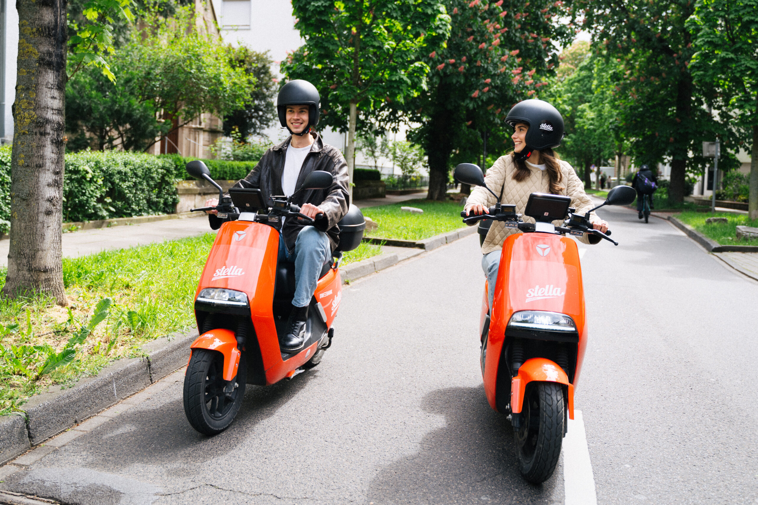 Zwei Personen fahren auf der Straße mit einem stella e-Moped.