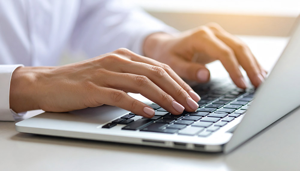 Nahaufnahme einer Hand. Person tippt auf einer Laptop-Tastatur.